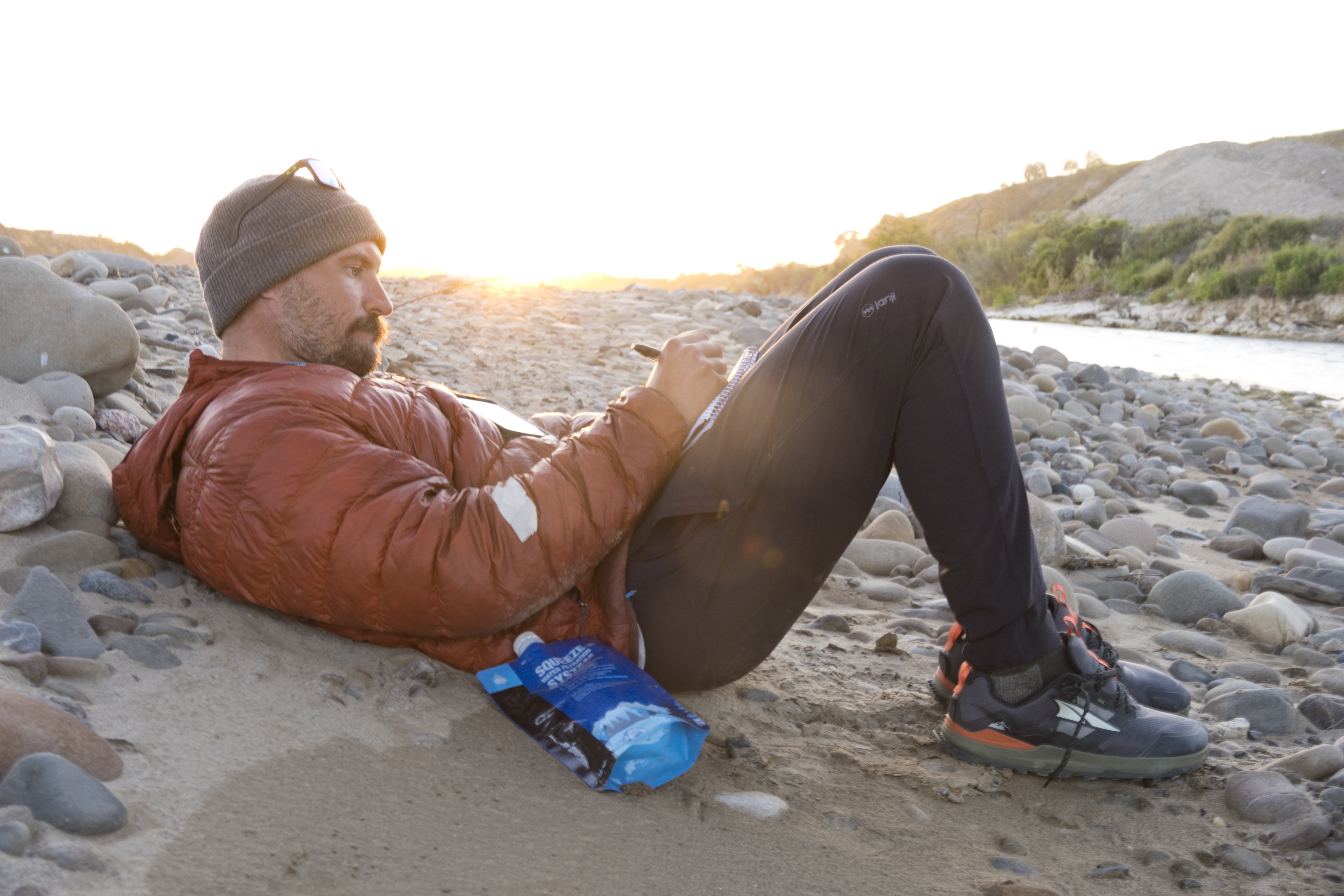 Sean Jansen journaling on beach with Squeeze system at his side.